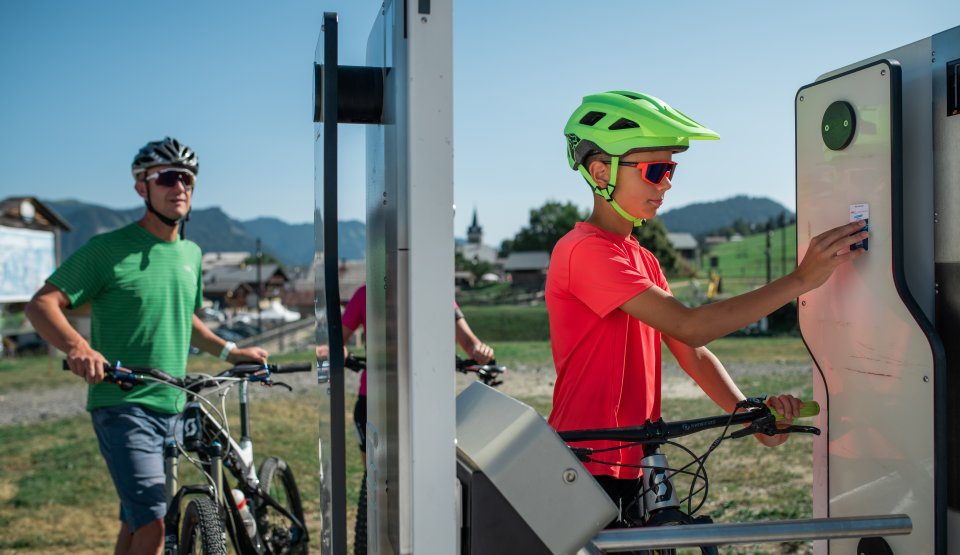 Un enfant et son père passent à la borne de la remontée mécanique de la Logère avec leurs Vélos